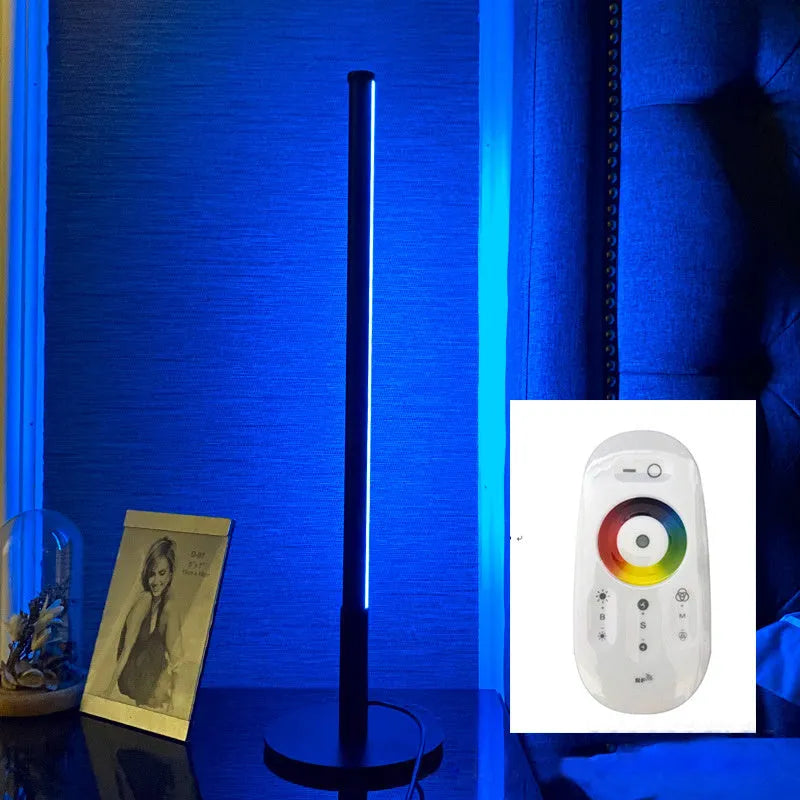 Tall black Nordic minimalist table lamp with RGB LED light on a wooden bedside table.