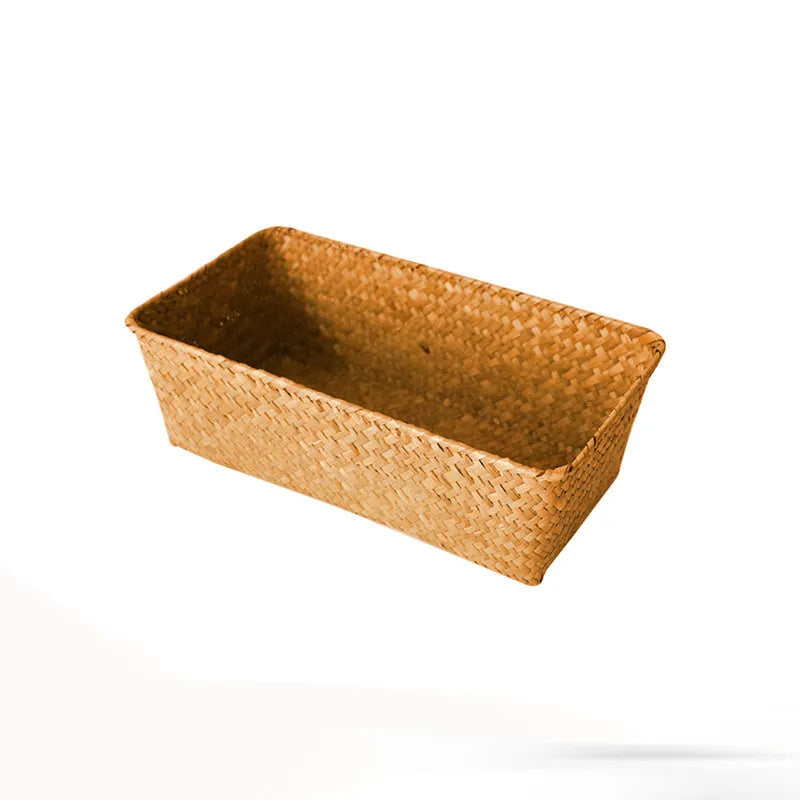 Woven straw desk storage box with lid in brown, shown alongside cosmetics and pens.
