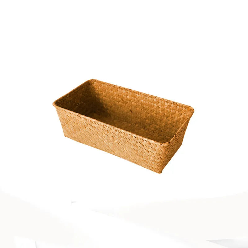 Woven straw desk storage box with lid in brown, shown alongside cosmetics and pens.