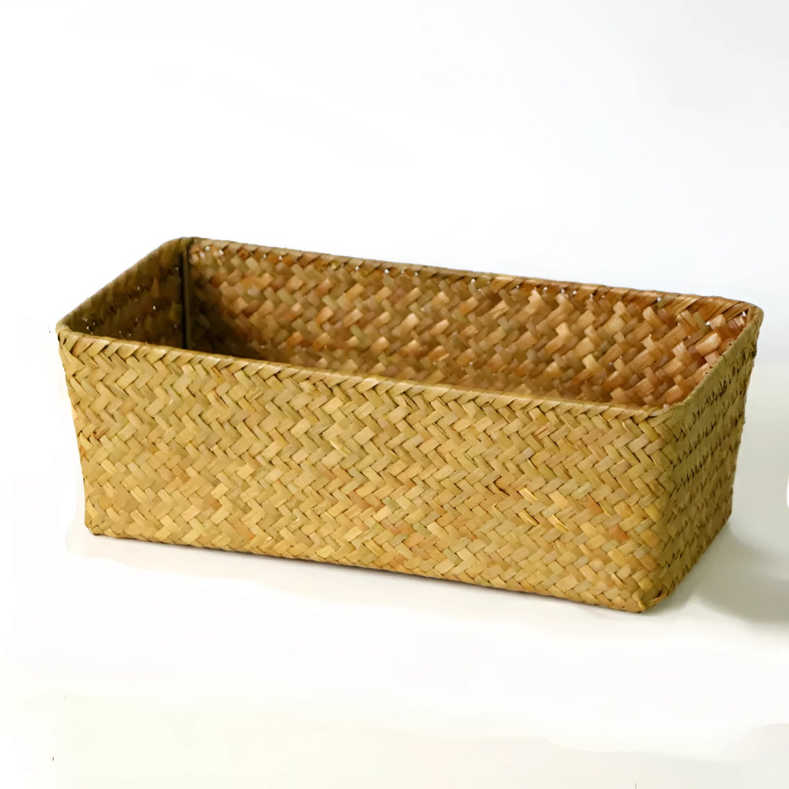 Woven straw desk storage box with lid in brown, shown alongside cosmetics and pens.
