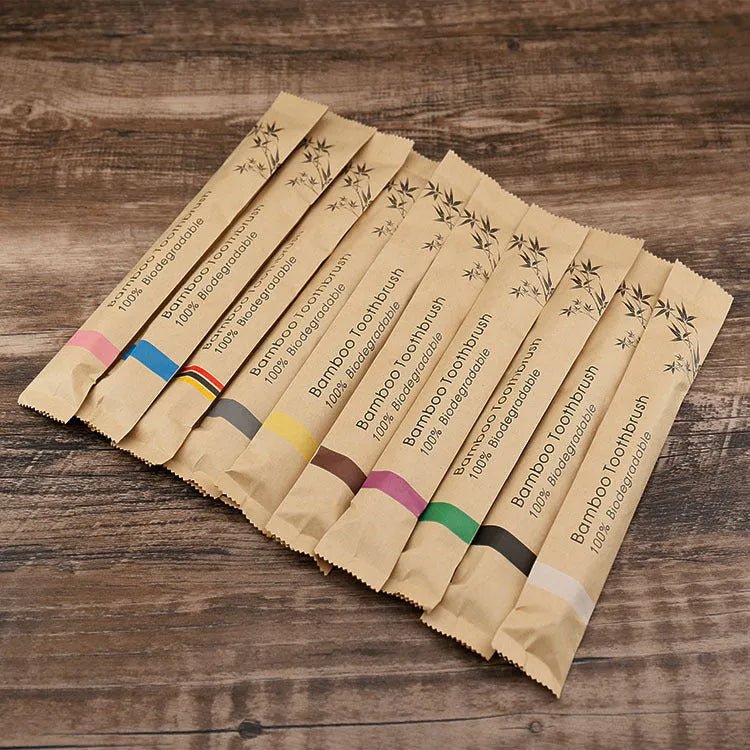 Ten bamboo toothbrushes with charcoal bristles in assorted colours on a white background.