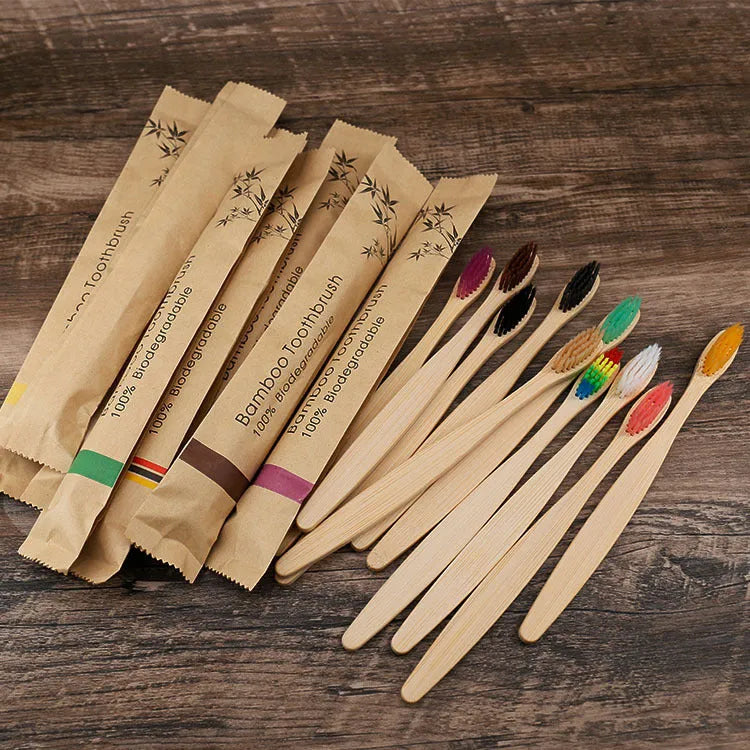 Ten bamboo toothbrushes with charcoal bristles in assorted colours on a white background.