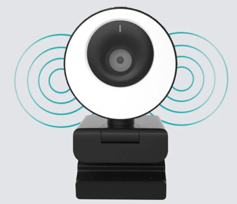 Black USB computer webcam with a magnetic privacy cover on a desk next to a laptop.