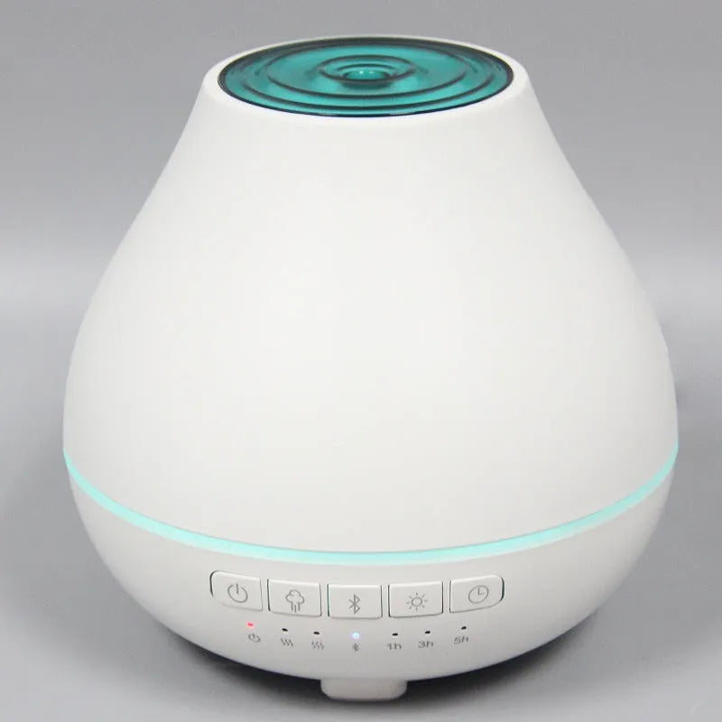 Round white Bluetooth humidifier and aroma diffuser with night light on a wooden surface.