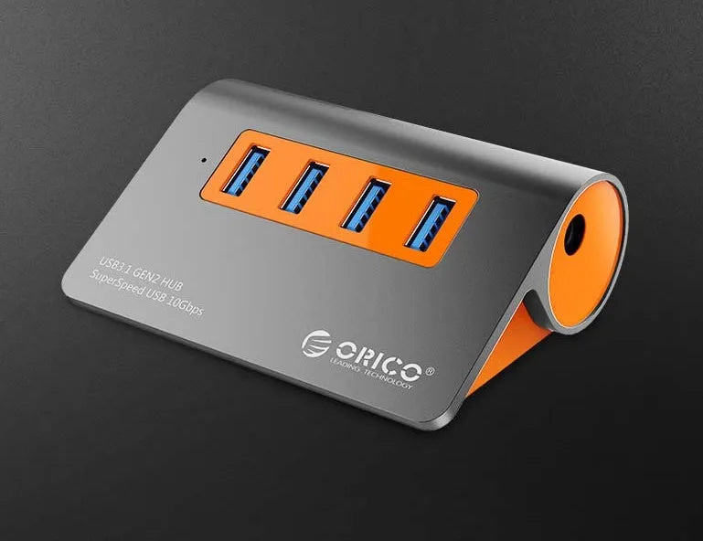 Dark grey and orange aluminium USB 3.1 laptop hub with four ports, separate cable, and power adapter