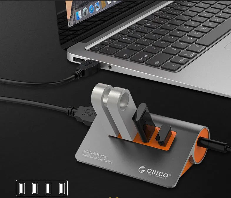 Dark grey and orange aluminium USB 3.1 laptop hub with four ports, separate cable, and power adapter