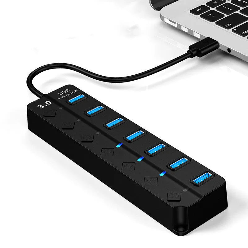 Black 7-port USB 3.0 hub with external power adapter on a desk