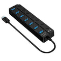 Black 7-port USB 3.0 hub with external power adapter on a desk