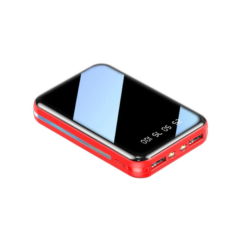 White portable power bank with digital display and two USB ports on a wooden table.