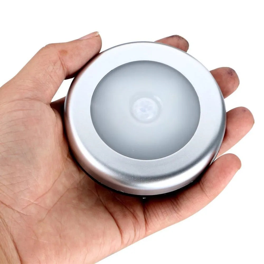 Silver circular motion sensor night light with 80mm diameter on table
