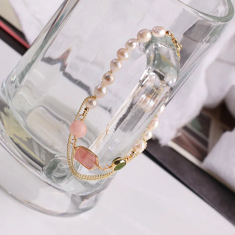 Close-up of a women's pink freshwater pearl bracelet with a strawberry crystal charm in a geometric design.