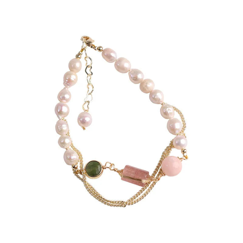 Close-up of a women's pink freshwater pearl bracelet with a strawberry crystal charm in a geometric design.