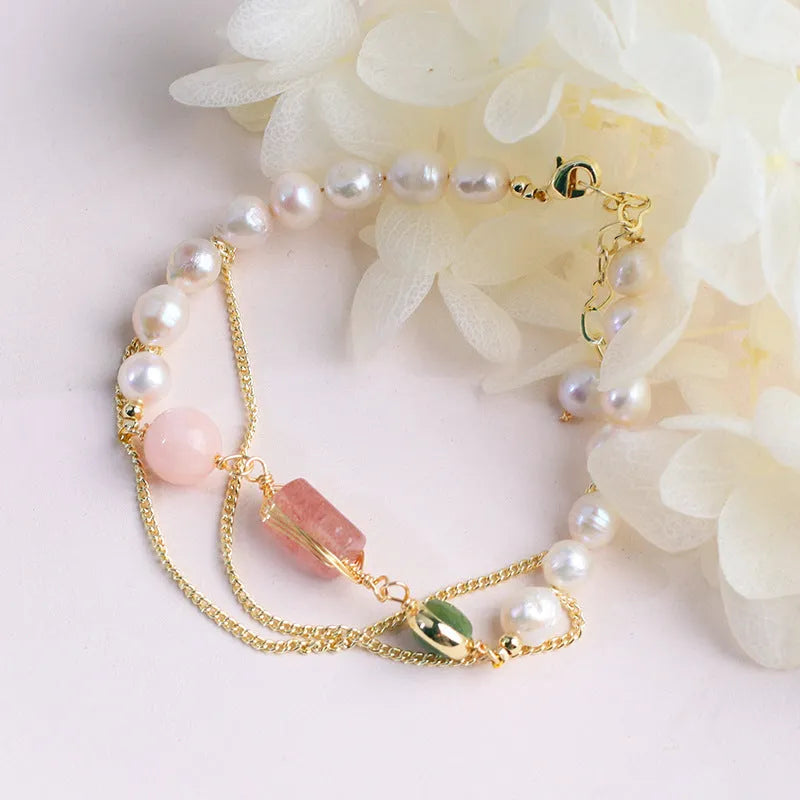Close-up of a women's pink freshwater pearl bracelet with a strawberry crystal charm in a geometric design.