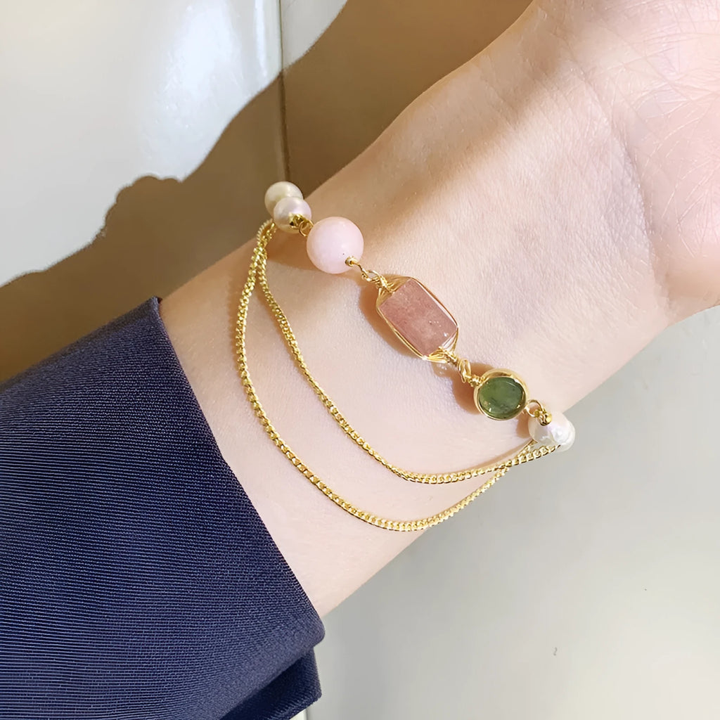 Close-up of a women's pink freshwater pearl bracelet with a strawberry crystal charm in a geometric design.