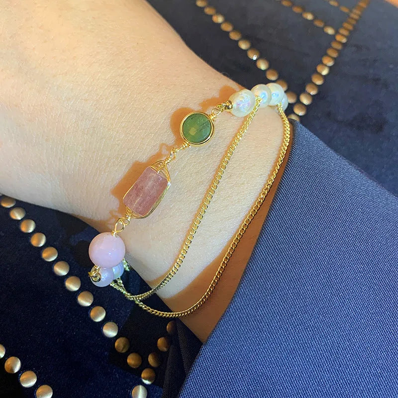 Close-up of a women's pink freshwater pearl bracelet with a strawberry crystal charm in a geometric design.