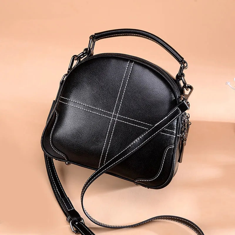 Round leather handbag with double soft handles and a zipper opening in a wine red colour.