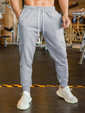 Man wearing loose grey linen-style trousers with an elastic drawstring waist, side view.