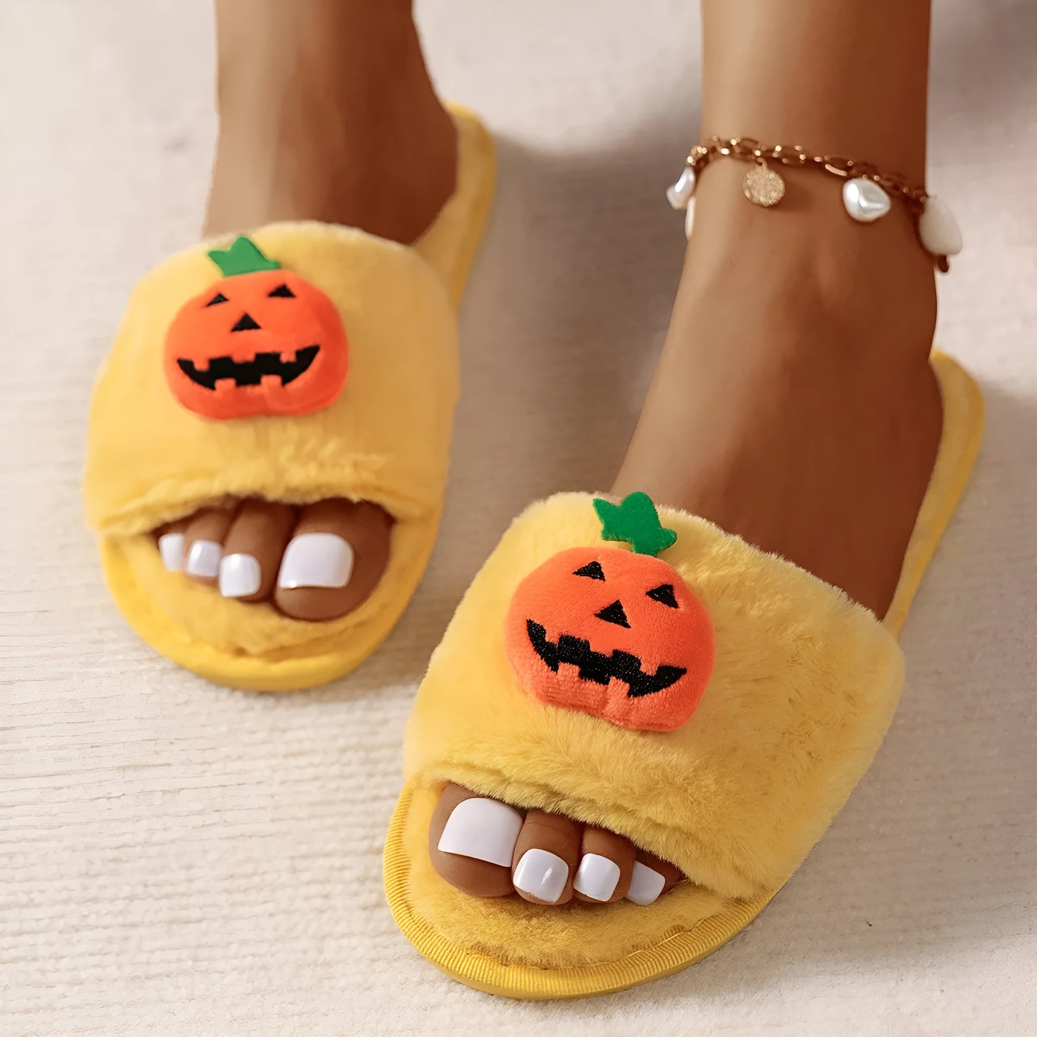 Yellow pumpkin plush open-toe slippers with a cartoon face, shown on a white background.
