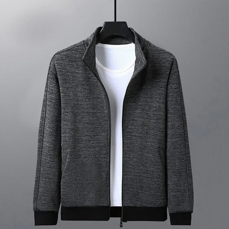Man wearing a grey athletic fit jacket with a standing collar and front zipper.