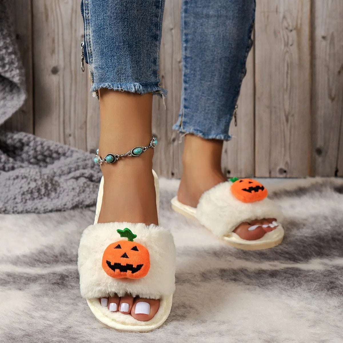 Yellow pumpkin plush open-toe slippers with a cartoon face, shown on a white background.