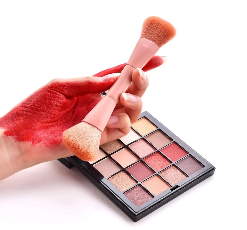 Ten wooden-handle make-up brushes for face and eye application in a pink travel case.