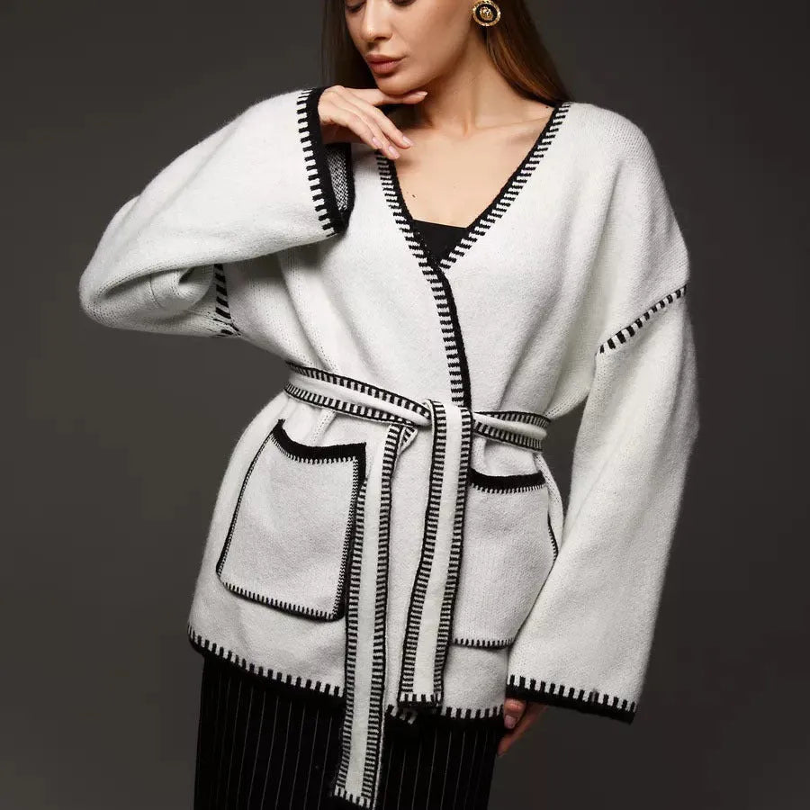 Loose mid-length knitted cardigan sweater coat with a lace-up front, shown in a neutral colour.