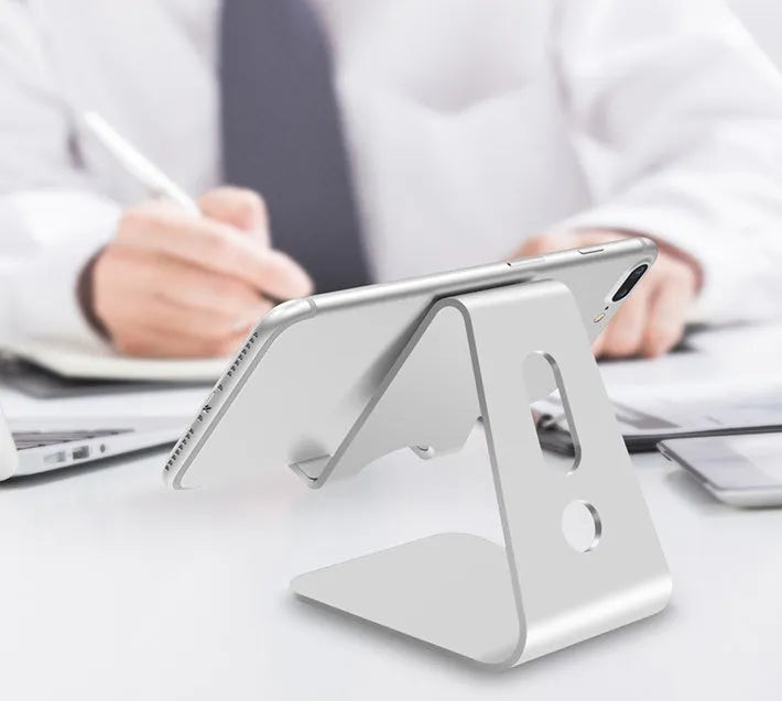 Metal universal phone and tablet stand in black, red, rose gold, and silver colours on a wooden table