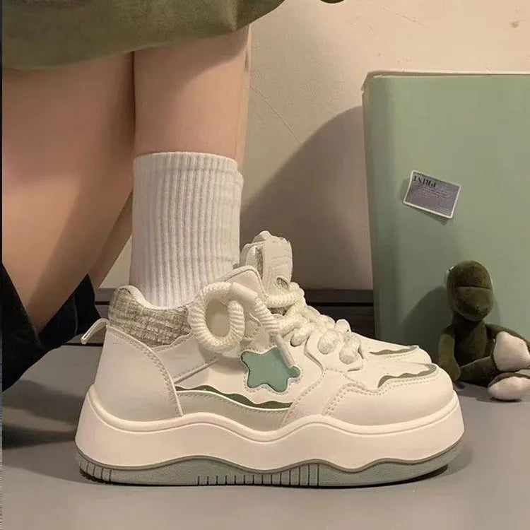 Women's green patent leather platform sneaker with round toe and white rubber sole on a pink background.