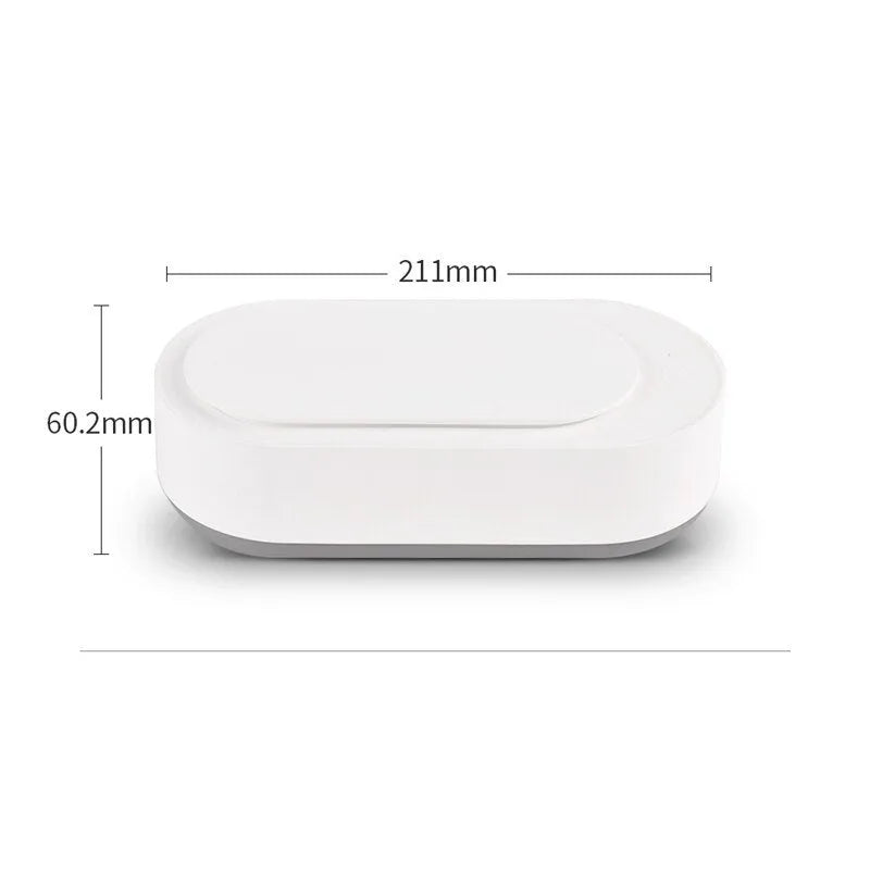 White portable ultrasonic cleaner with touch button next to jewellery and glasses on a table.