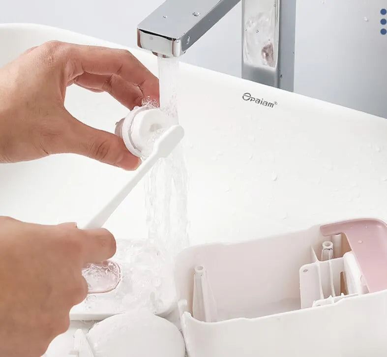 A blue automatic toothpaste dispenser mounted on a bathroom wall with a soft-touch button.
