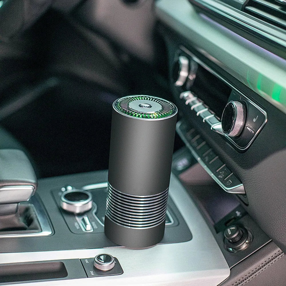 Compact black car air purifier with aluminium alloy body, shown with power cord.