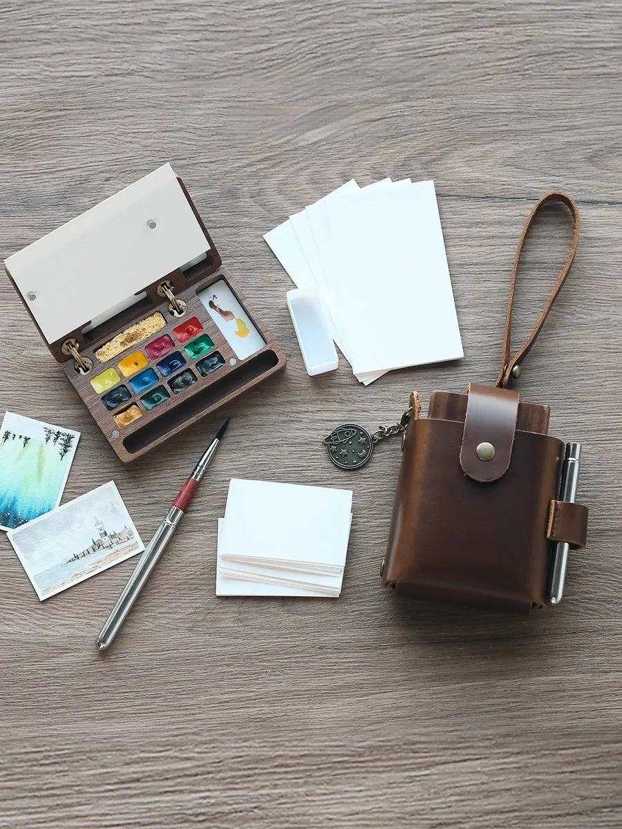 Mini solid walnut wood watercolour paint box with open lid showing internal compartments for half-pan pigments.