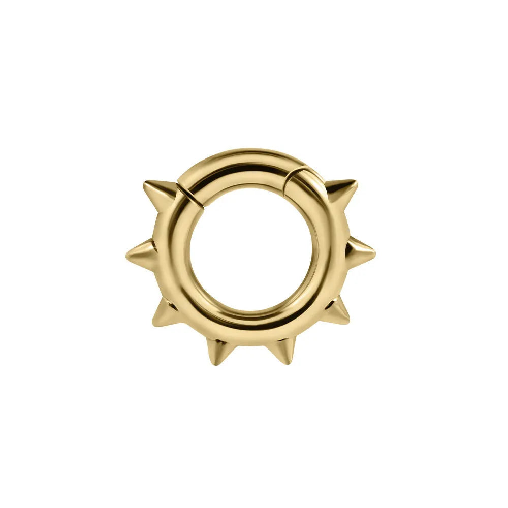 A pair of sharp cone-shaped copper ear extenders with a round magnetic closure on a flat surface.