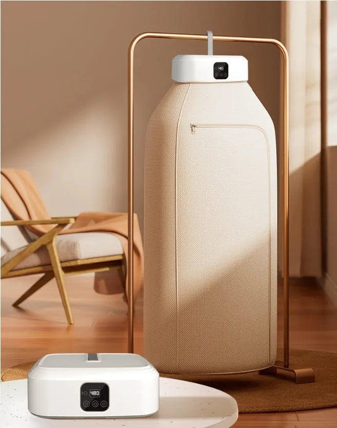 White cylindrical foldable clothes dryer with remote control on a table.