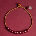 Close-up of a geometric design bracelet made from dark red cinnabar and Hetian jade on a wrist.