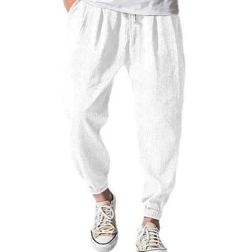 Man modelling loose fit cotton trousers with elasticated ankle cuffs in a light green colour.