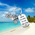 Stainless steel motorcycle key chain with charm and grey flannel storage bag.