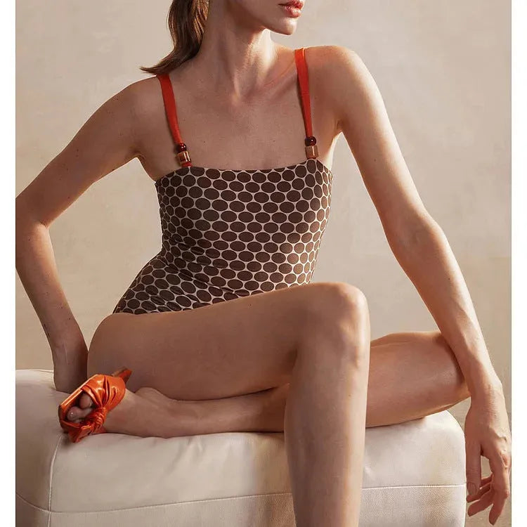 Women's blue dot print one-piece swimsuit with a matching wrap skirt laid flat.