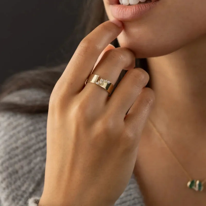 Gold electroplated copper ring for women with shining zircon accents, shown on a finger.