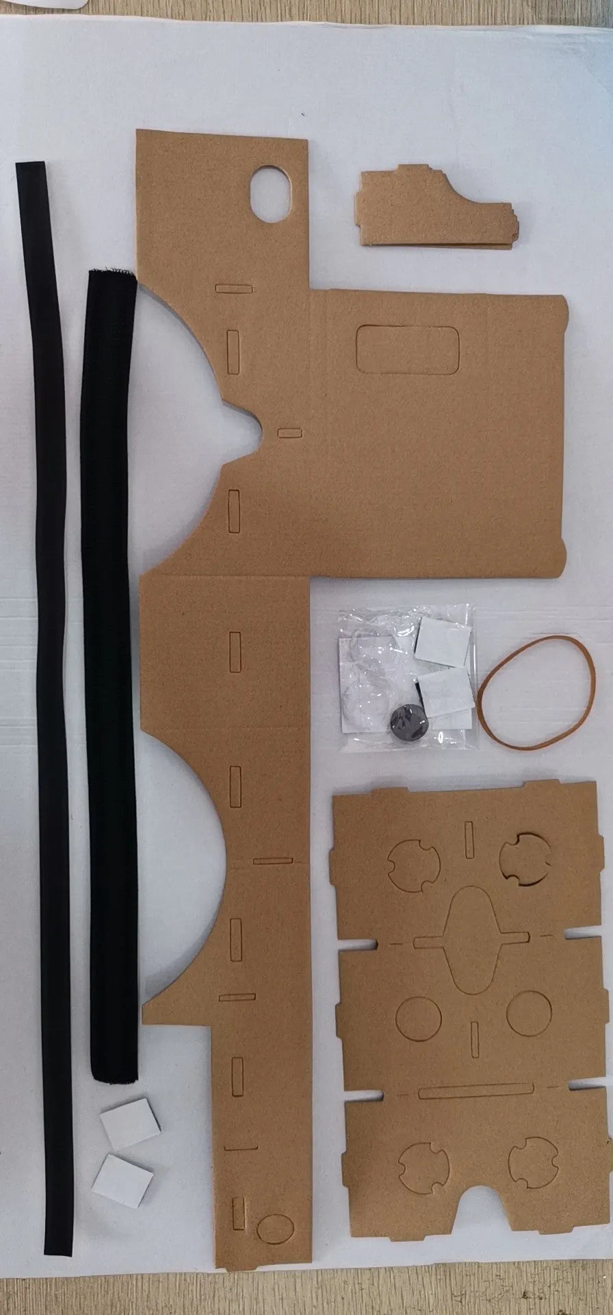 Pink and white foldable cardboard VR glasses headset for smartphones, showing 3D lenses and rubber head strap.