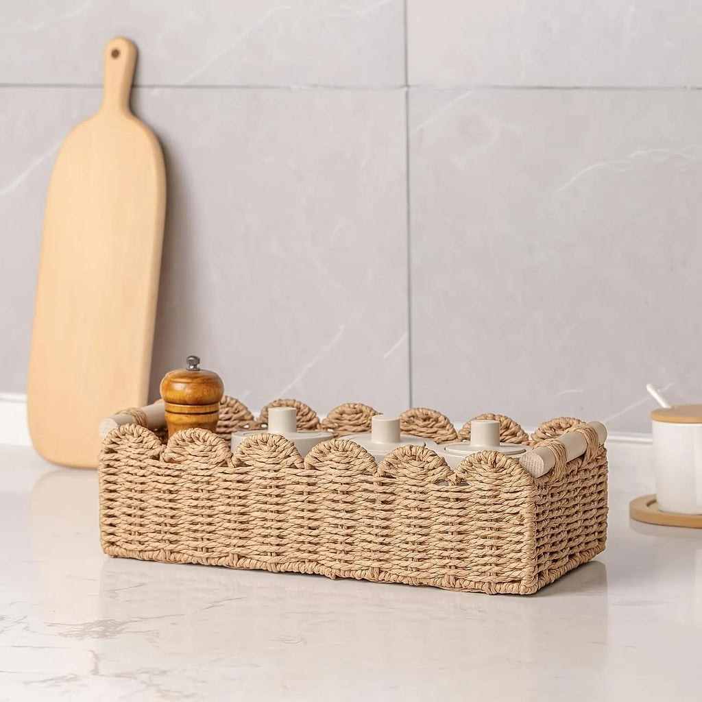 Woven paper storage basket in khaki colour on a wooden desk holding remote controls and pens.