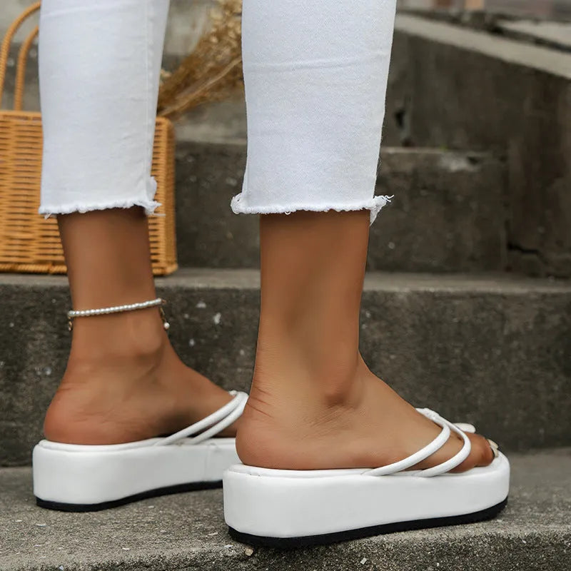 Thick sole herringbone pattern flip-flops in multiple colours on a beach background.