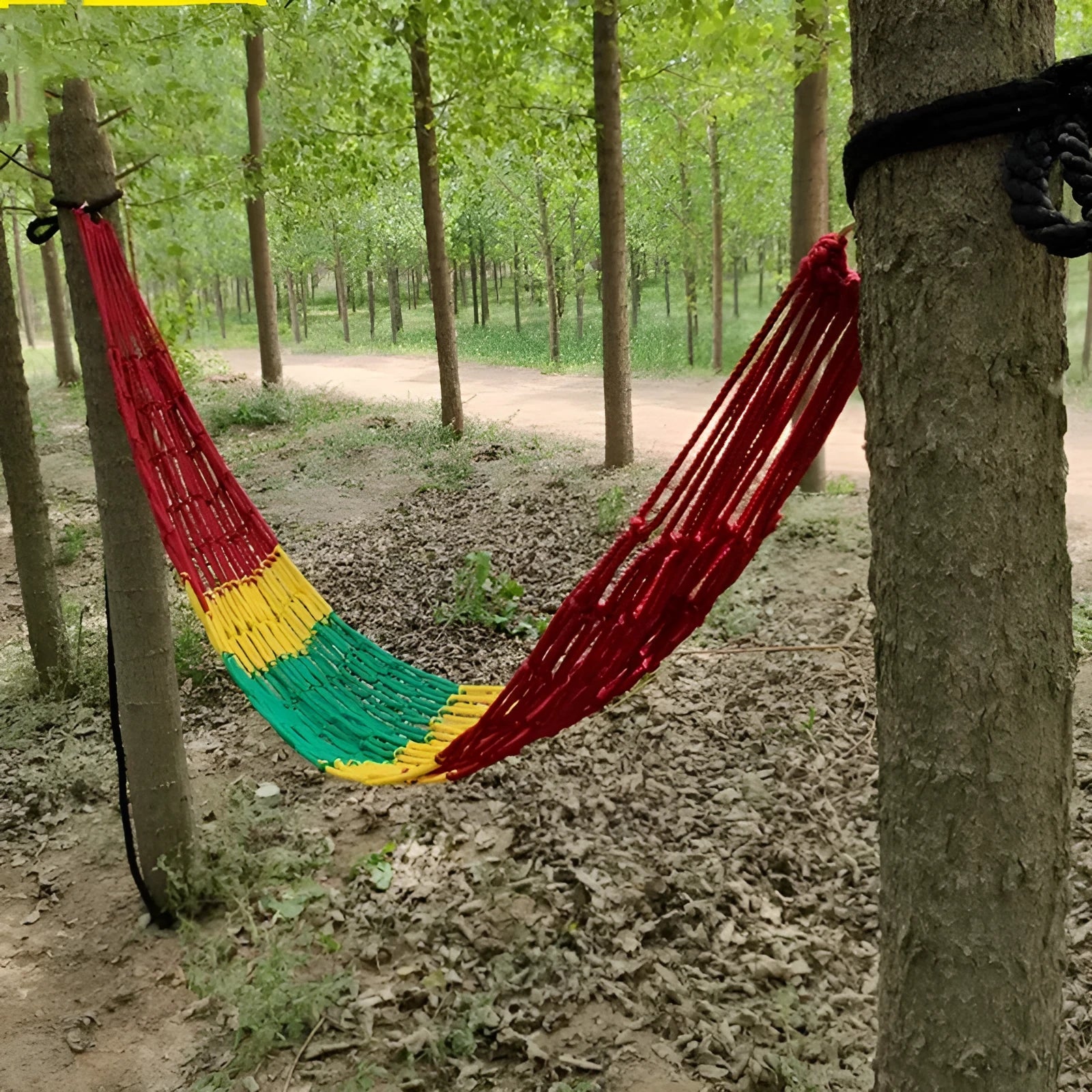 Nylon rope mesh hammock hung outdoors, showing its woven design and included tying ropes.