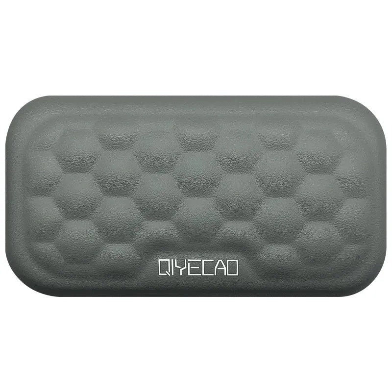 Black memory foam mouse wrist pad with a leather-style cover on a wooden desk