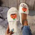 Yellow pumpkin plush open-toe slippers with a cartoon face, shown on a white background.