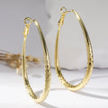 Gold egg-shaped copper earrings with hypoallergenic posts and spring fasteners, unisex geometric ellipse design
