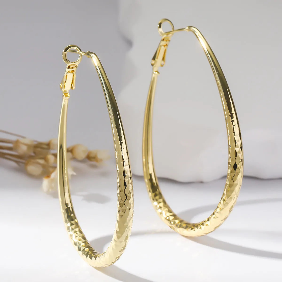 Gold egg-shaped copper earrings with hypoallergenic posts and spring fasteners, unisex geometric ellipse design