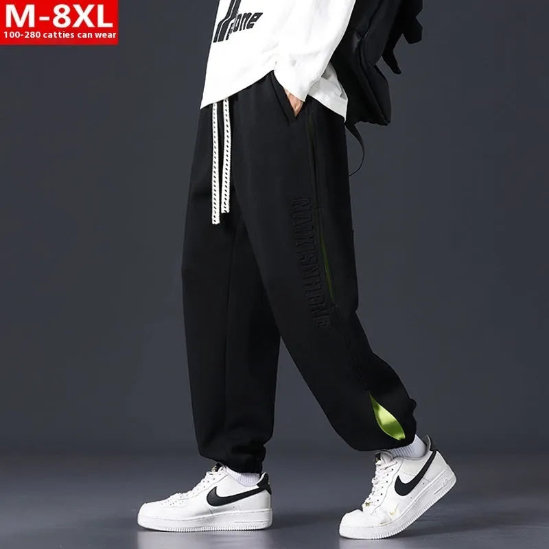 Man wearing grey green loose-fit cotton trousers with stitching print detail and an ankle band.