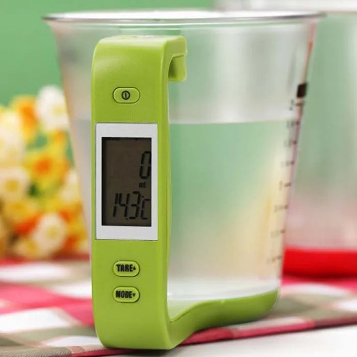 Green digital kitchen measuring cup with integrated LCD display showing weight and temperature measurements