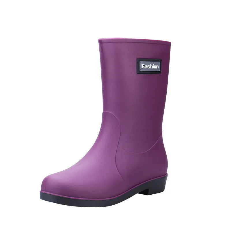 Women's black PVC mid-calf rain boot with a low heel on a wet surface.